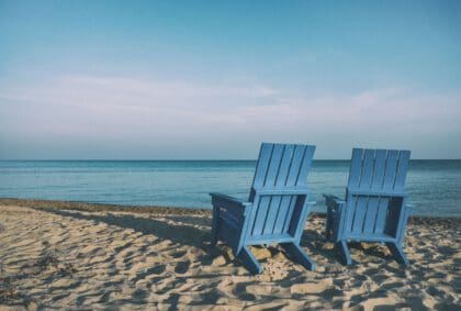 Zwei blaue Holzstühle am Strand