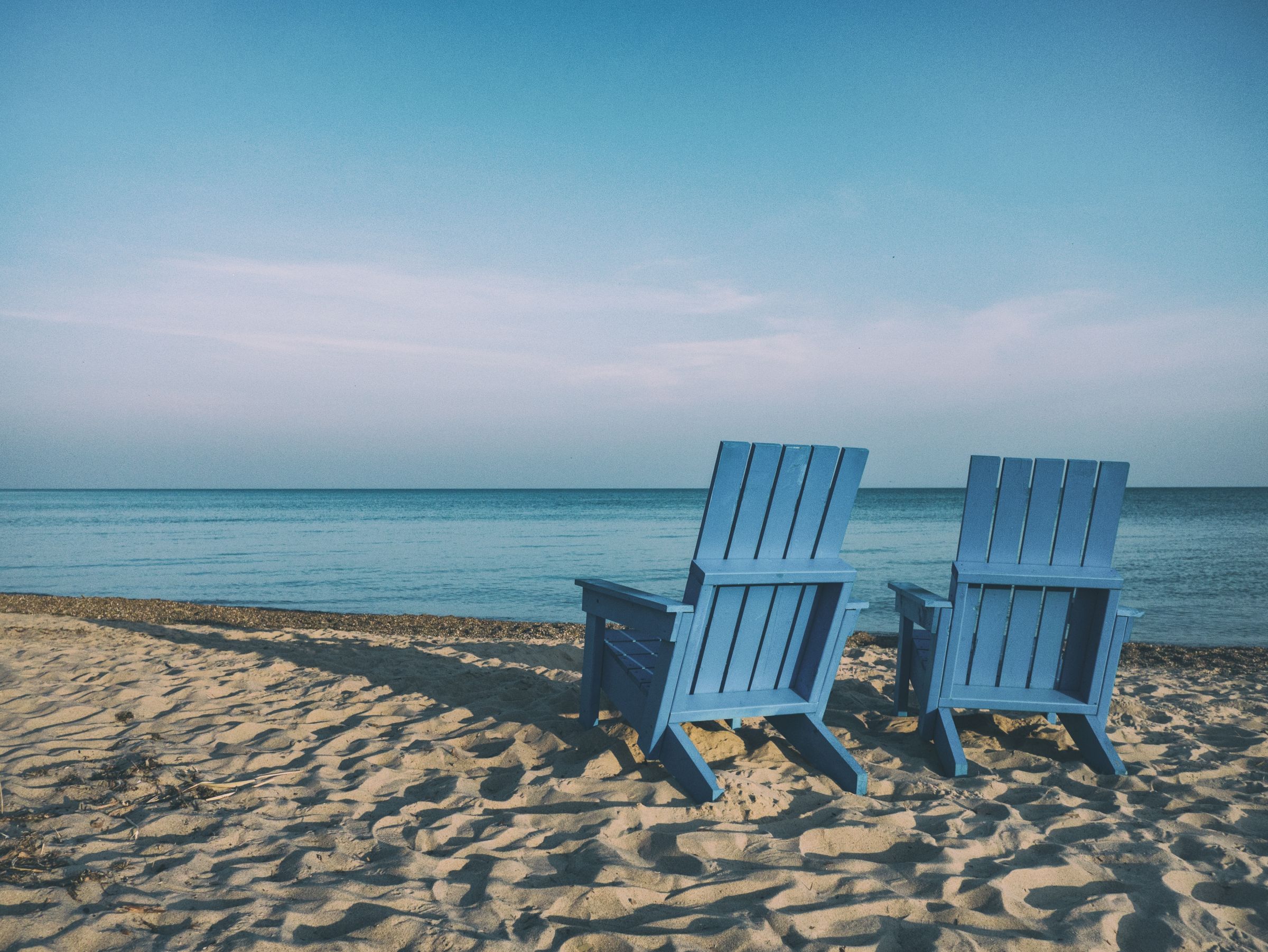 Zwei blaue Holzstühle am Strand